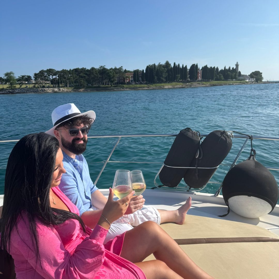  A couple in pink dress and white hat clinking wine glasses on bow sun-pad