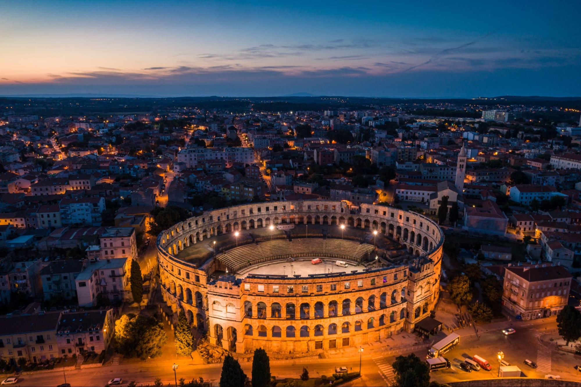 Pula Arena lit up at night with a view of the city  Pula Arena lit up at night with a view of the city