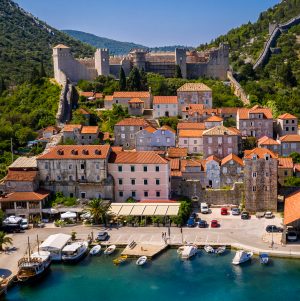 Aerial view of the historic town of Ston, Croatia, with medieval stone walls, terracotta-roofed houses, and a waterfront lined with boats
