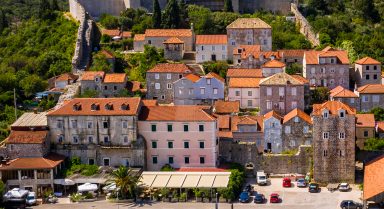Luftansicht der historischen Stadt Ston, Kroatien, mit steinernen Wehrmauern aus dem Mittelalter, H&auml;usern mit Terracotta-D&auml;chern und einem Hafengebiet mit aneinandergereihten Booten