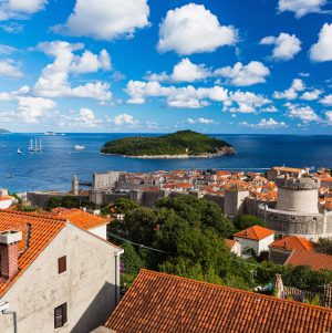 View of Lokrum Island from Dubrovnik’s Old Town, with terracotta rooftops, medieval city walls, and the Adriatic Sea in the background.