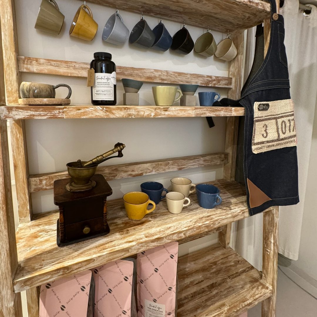 Rustic wooden shelf at Coffee Snob in Hvar displaying mugs, coffee beans, grinders, and branded items.