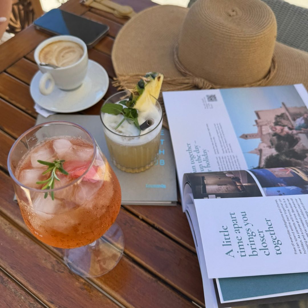 Table with a coffee, cocktails, a hat, a magazine and a phone. Table with a coffee, cocktails, a hat, a magazine and a phone.