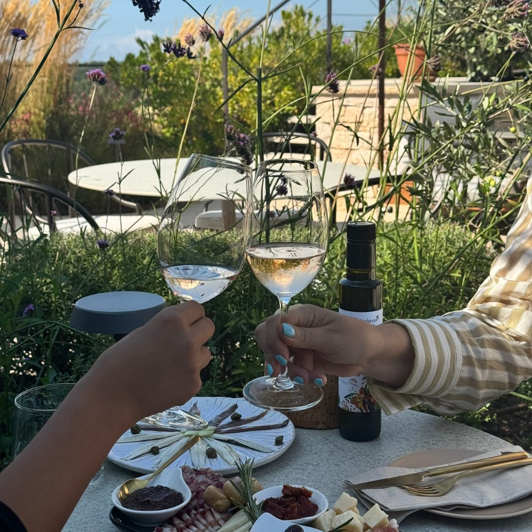 Toasting with glasses of wine over a table set with Istrian delicacies at Radovan Wines terrace. Toasting with glasses of wine over a table set with Istrian delicacies at Radovan Wines terrace.