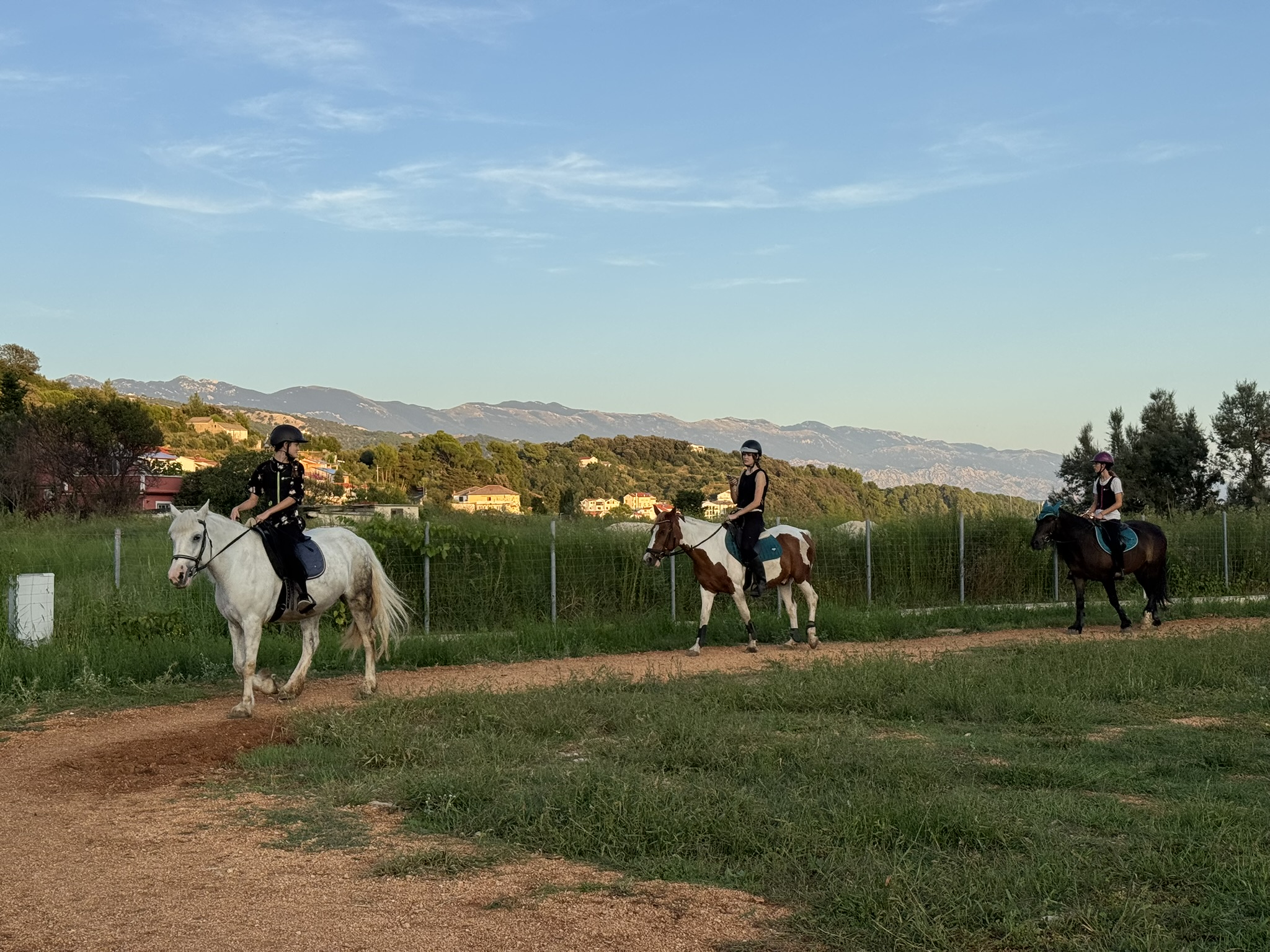 Group of riders on horseback at Soline Ranch, Rab Island, with rolling hills and mountains in the background at sunset. Group of riders on horseback at Soline Ranch, Rab Island, with rolling hills and mountains in the background at sunset.