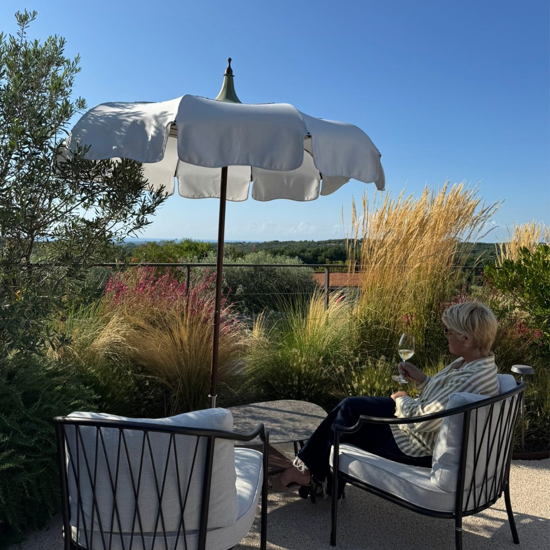 Guest relaxing with a glass of wine under a white umbrella at Radovan Wines terrace. Guest relaxing with a glass of wine under a white umbrella at Radovan Wines terrace.