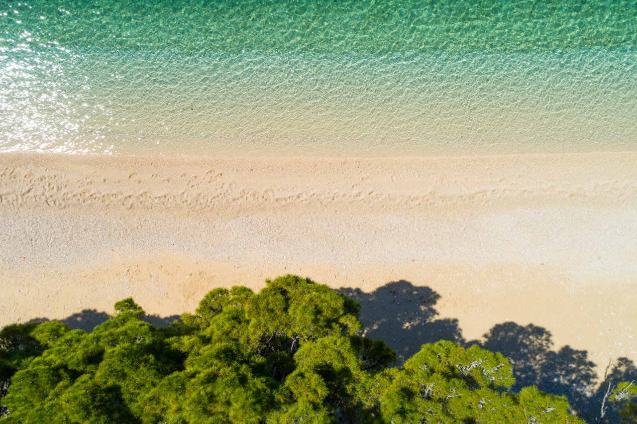 Aerial view of a sandy-pebble beach with turquoise sea and pine trees near Hotel Meteor in Makarska.  Aerial view of a sandy-pebble beach with turquoise sea and pine trees near Hotel Meteor in Makarska.