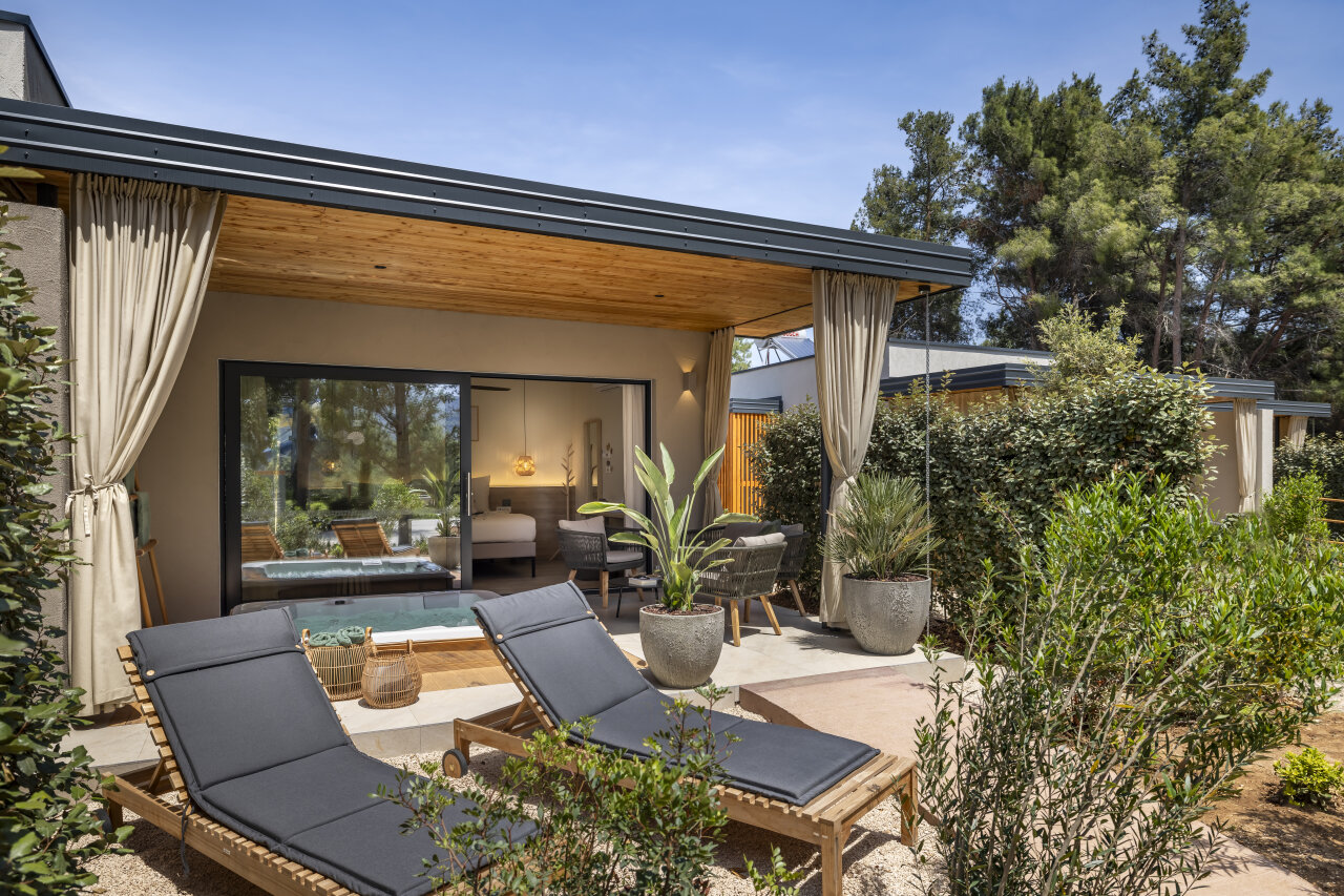 Private garden terrace of a Valamar Amicor Resort villa on Hvar with two sun loungers and an outdoor jacuzzi, framed by Mediterranean greenery.