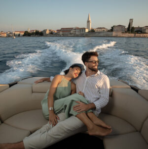 A couple relaxes on a luxury boat during sunset, with the historic coastal town of Poreč.