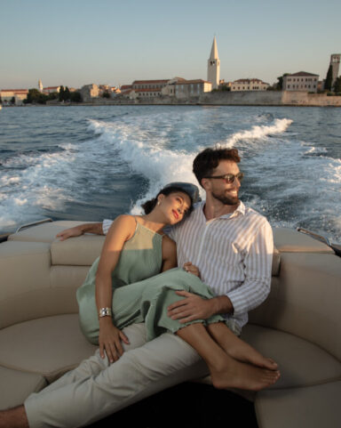 A couple relaxes on a luxury boat during sunset, with the historic coastal town of Poreč.
