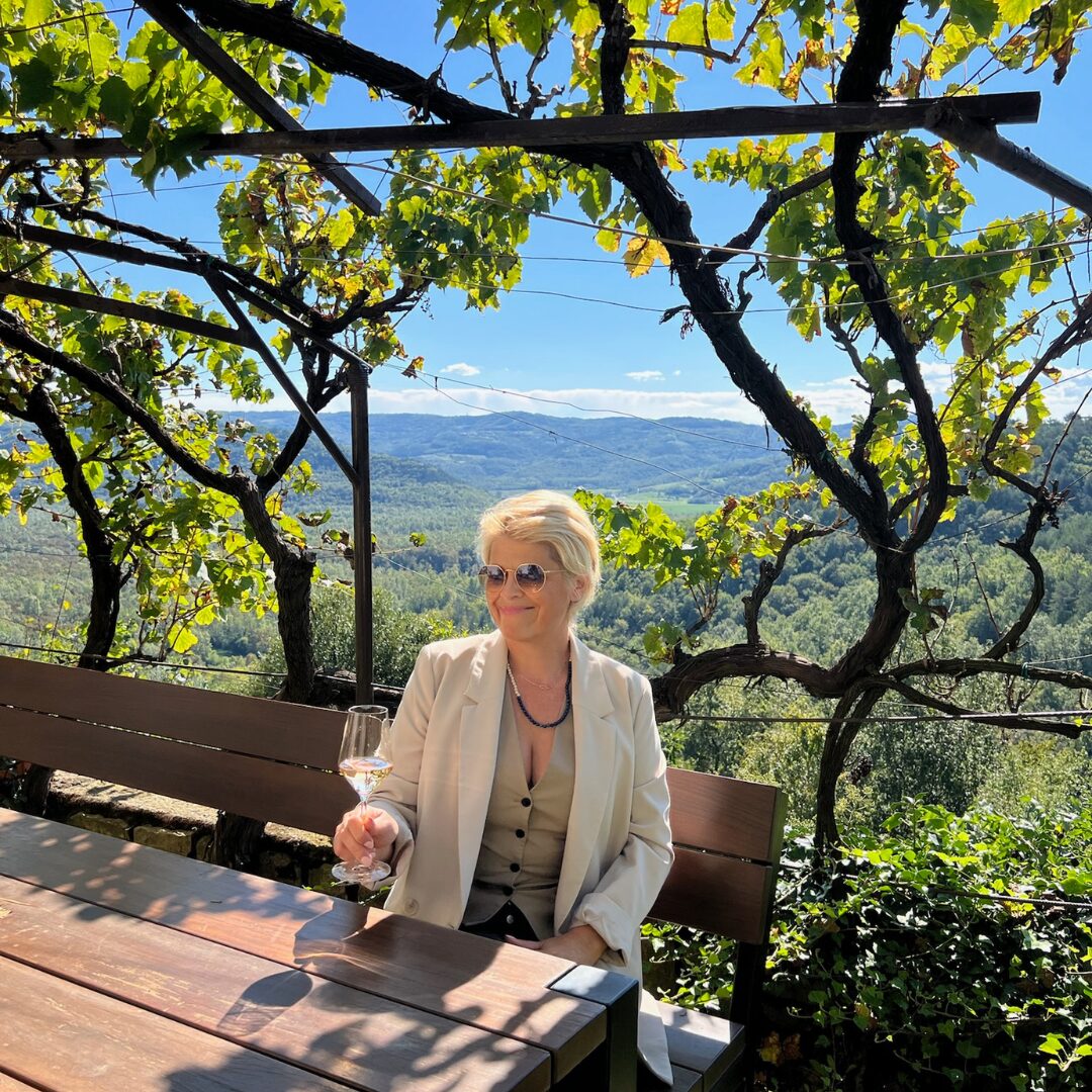 Ein Gast genießt ein Glas Wein auf einer von Weinreben umrankten Terrasse mit Blick auf die grünen Hügel Istriens. Ein Gast genießt ein Glas Wein auf einer von Weinreben umrankten Terrasse mit Blick auf die grünen Hügel Istriens.