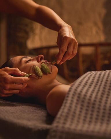 Woman enjoying a facial treatment with a jade roller.