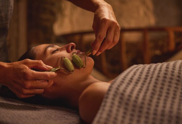 Woman enjoying a facial treatment with a jade roller.