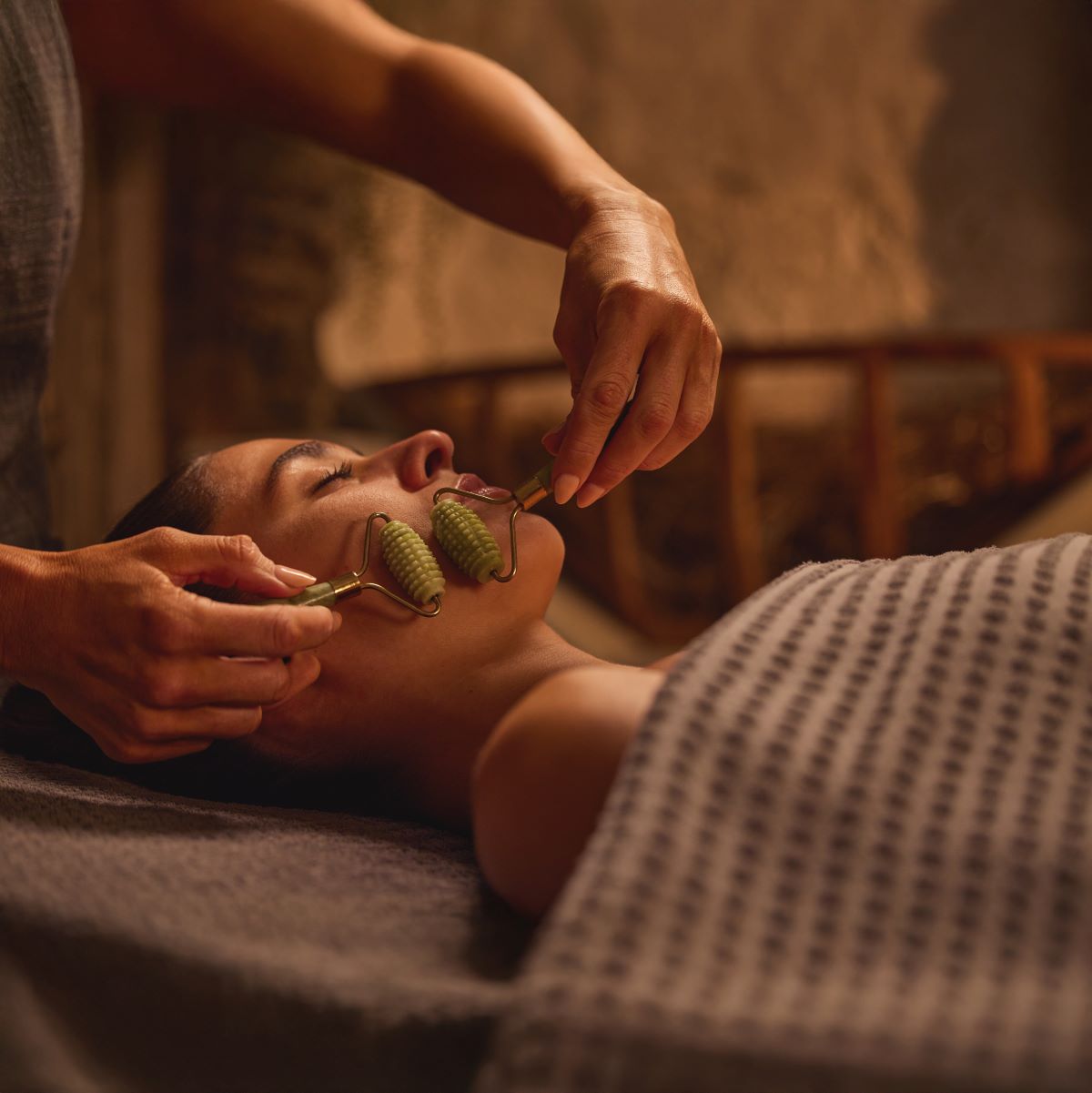 Woman enjoying a facial treatment with a jade roller. Woman enjoying a facial treatment with a jade roller.