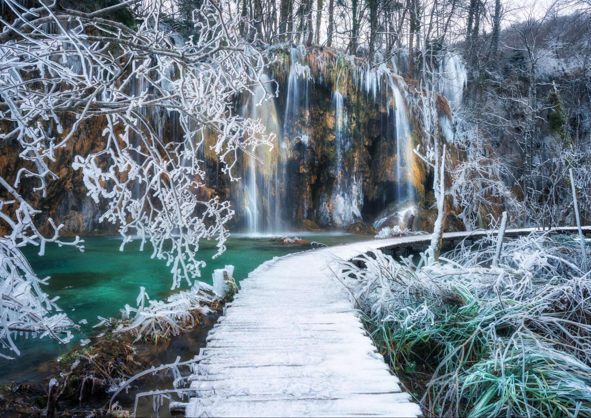 Plitvice Lakes National Park in winter with frozen waterfalls and snow-covered trails. Plitvice Lakes National Park in winter with frozen waterfalls and snow-covered trails.
