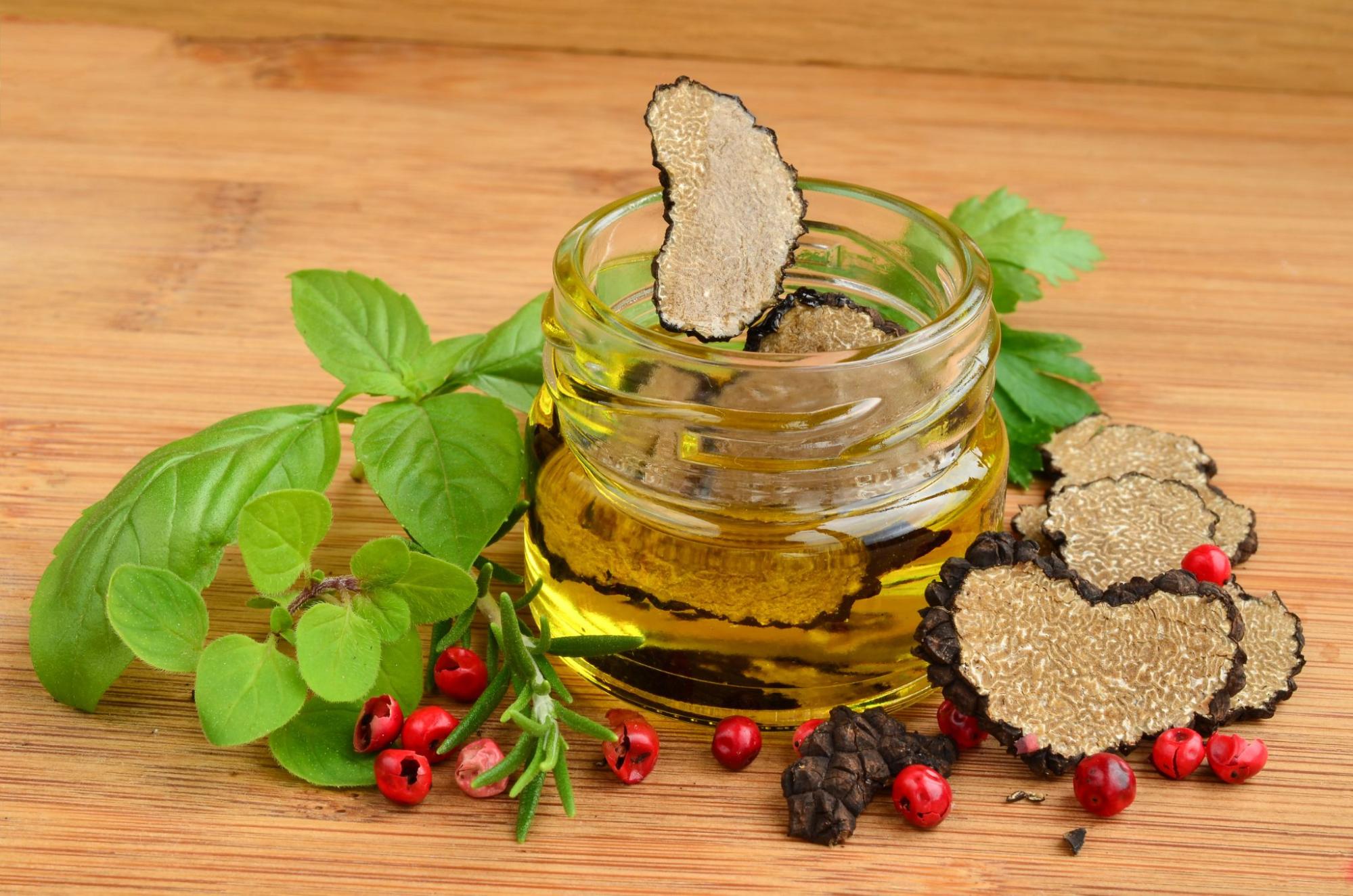 Istrian truffle olive oil with fresh herbs and peppercorns on a wooden table. Istrian truffle olive oil with fresh herbs and peppercorns on a wooden table.