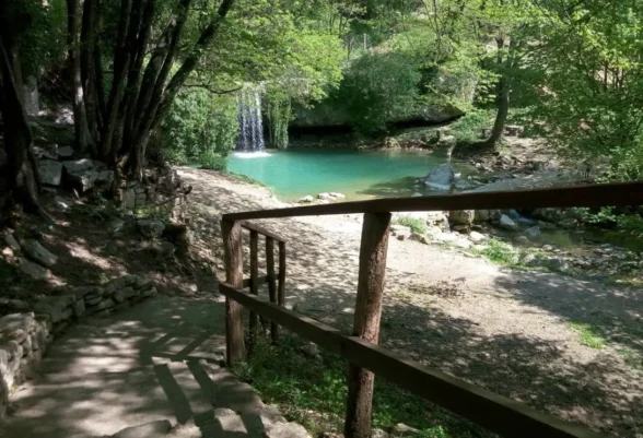 Der Wasserfall Gologorički Dol in Istrien mit seinem türkisfarbenen Becken und einem Waldweg.