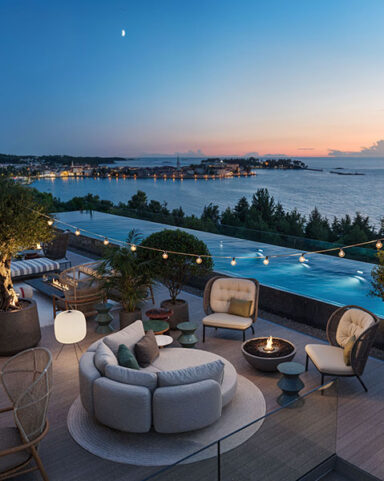 Rooftop Bar im Pical mit Olivenb&auml;umen, Feuerstellen und einem Infinity-Pool mit Blick auf das Meer und Poreč bei Sonnenuntergang.