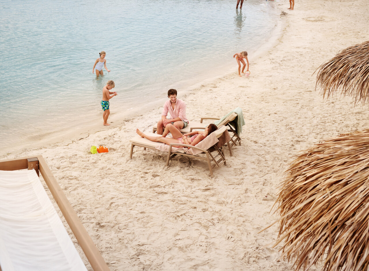 A family relaxing on sun loungers on a sandy beach at Valamar Padova Hotel on Rab Island. Eine Familie entspannt auf Sonnenliegen an einem Sandstrand beim Valamar Padova Hotel auf der Insel Rab.