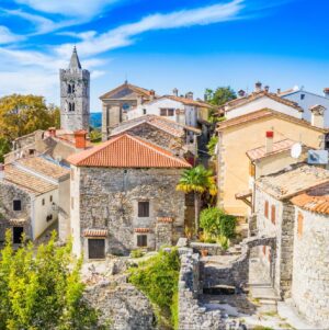 Eine Panoramaansicht von Hum, der kleinsten Stadt der Welt, mit Steinh&auml;usern und einem von Gr&uuml;n umgebenen Kirchturm