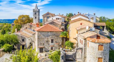Panorama of Hum, the world’s smallest town, with stone houses and a church tower surrounded by greenery
