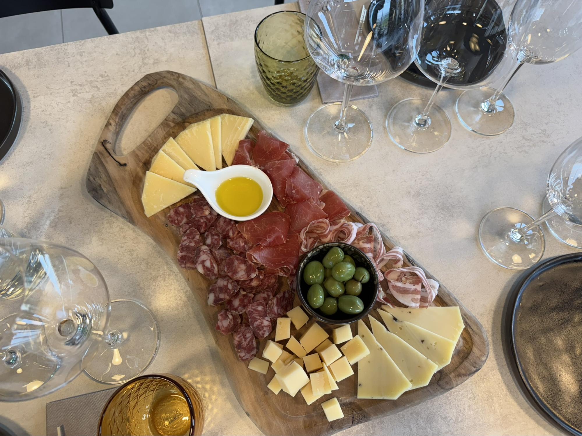 Wooden platter with Istrian cheeses, prosciutto, salami, olives, and olive oil served alongside wine glasses during a tasting. Wooden platter with Istrian cheeses, prosciutto, salami, olives, and olive oil served alongside wine glasses during a tasting.