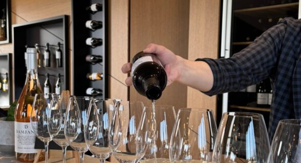 A sommelier pouring white wine into tasting glasses at a modern wine bar inside Damjanić winery.