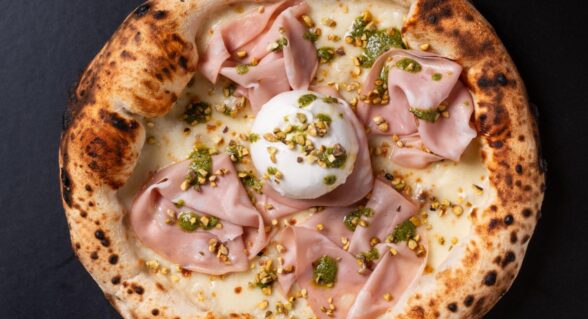 Pizza mit Mortadella und Pistazien auf dunklem Teller