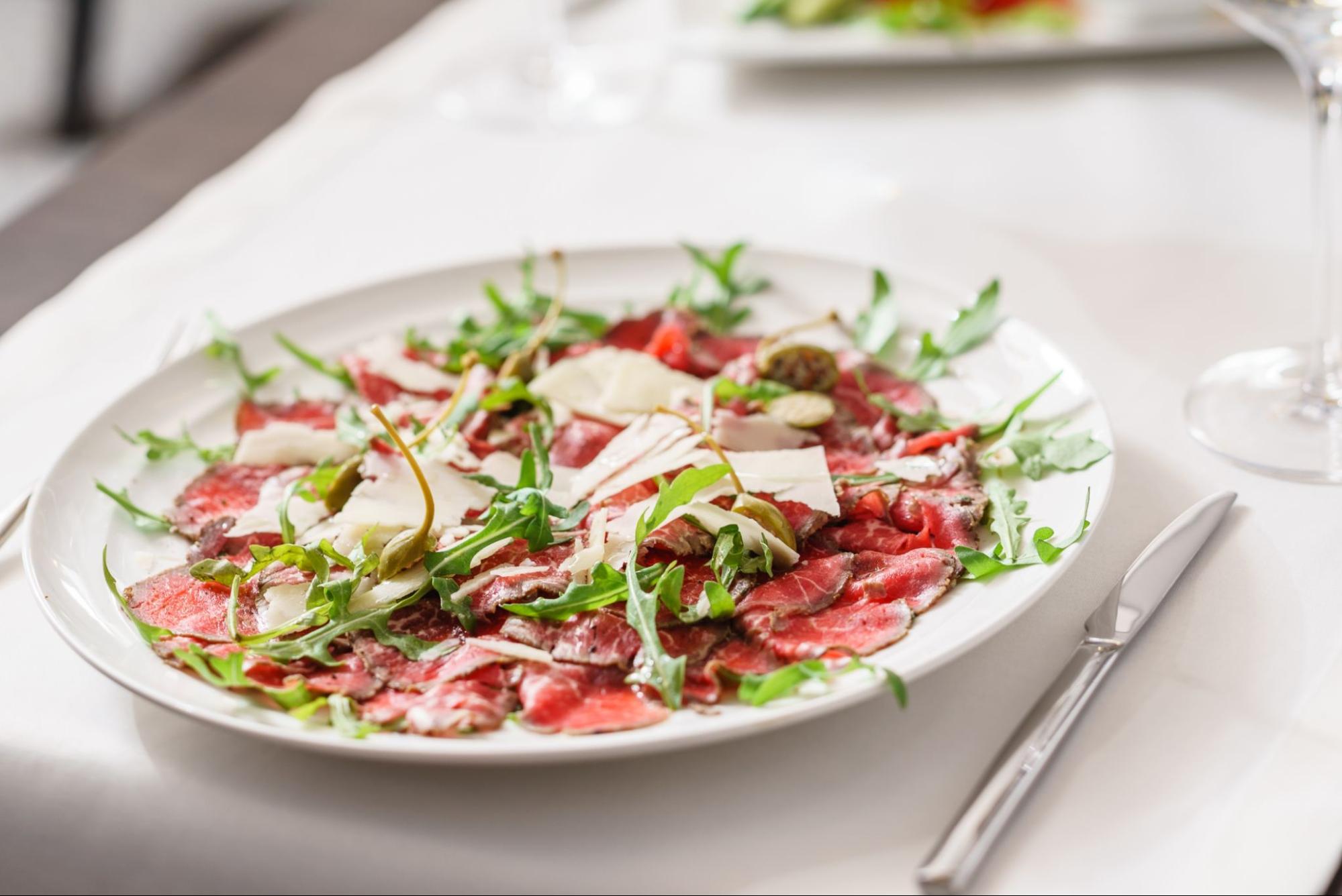 Bo&scaron;karin carpaccio served with rocket and Grana Padano cheese