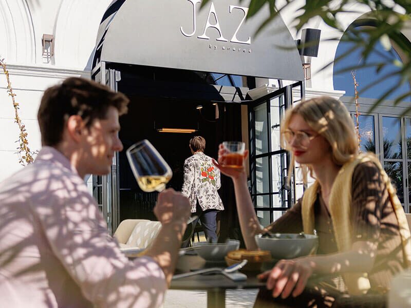 Couple enjoying food and drinks on the sunny terrace of JAZ by Ana Ro&scaron; in Poreč, Istria