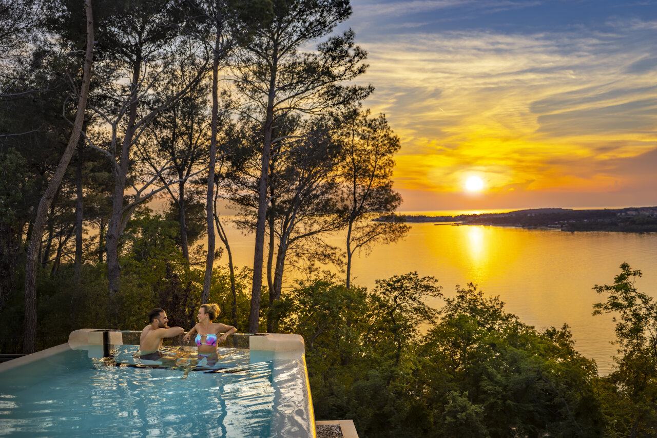 Ein Paar im Infinity-Pool des Punto Blu Valamar Camping Village genie&szlig;t den Sonnenuntergang &uuml;ber dem Meer in Istrien