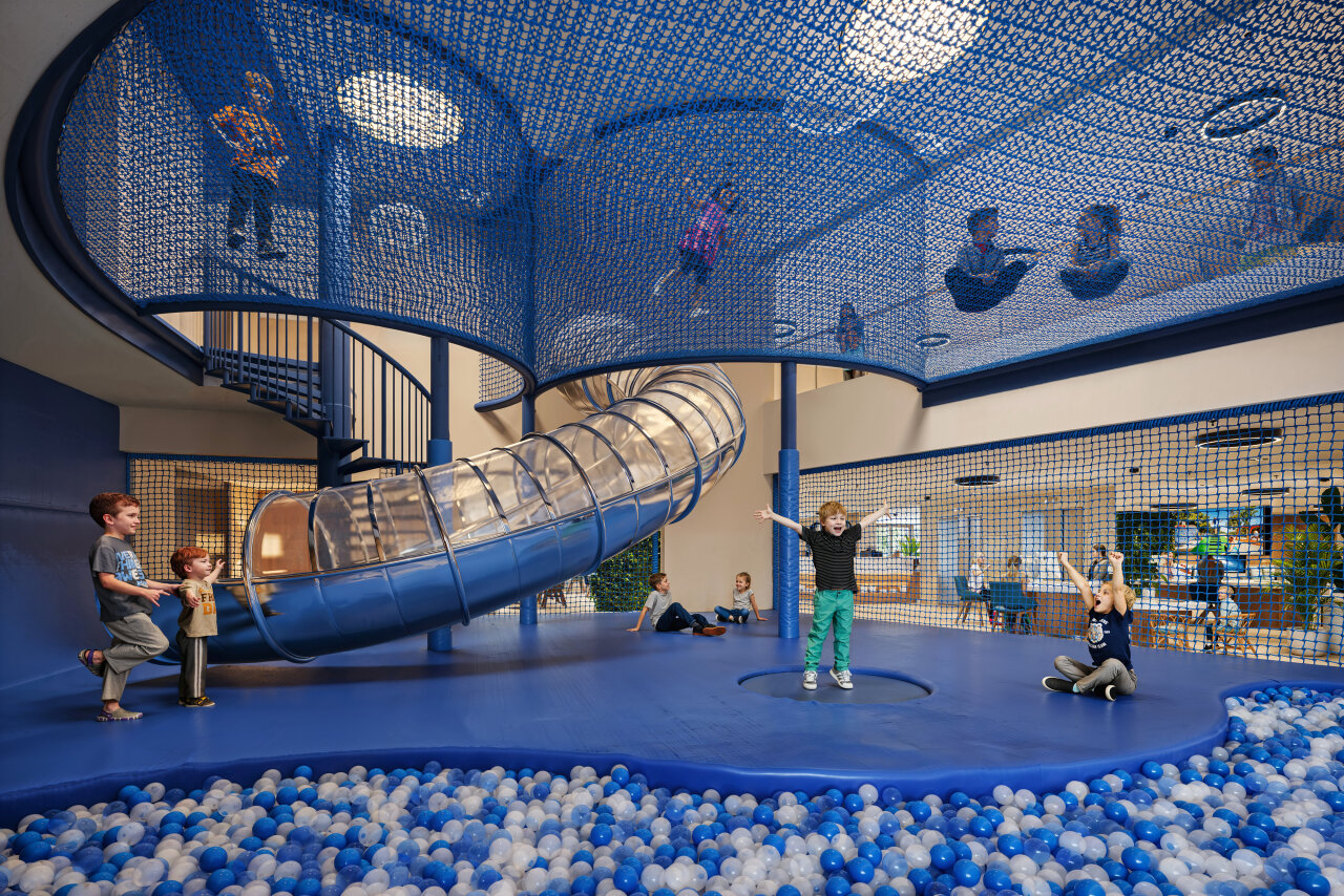 Children playing in a large playroom with a slide, climbing nets and a ball pit at Pical Resort 5* 