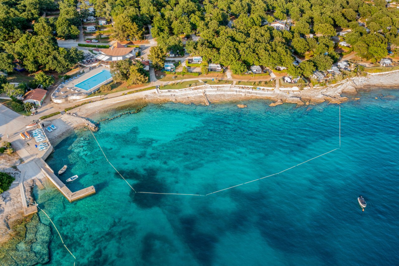 Luftaufnahme von Camping Solaris, einem FKK-Campingplatz mit kristallklarem Meer und dichtem Pinienwald