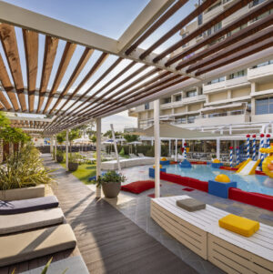 An outdoor children&rsquo;s pool with slides, sprinklers and a relaxation area in a family resort.