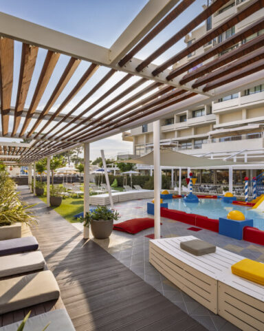 An outdoor children&rsquo;s pool with slides, sprinklers and a relaxation area in a family resort.