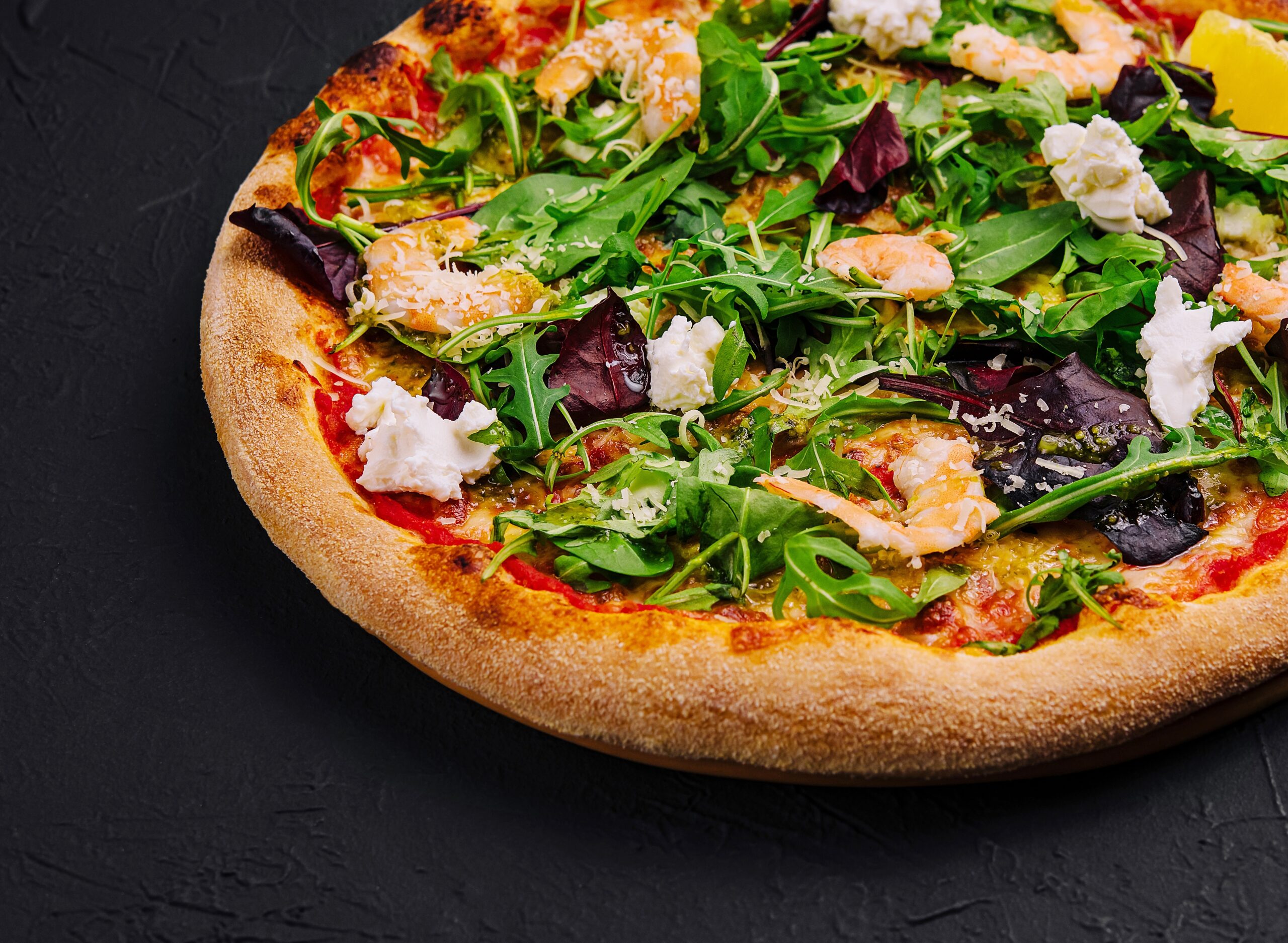 Richly topped pizza with olives on a dark surface